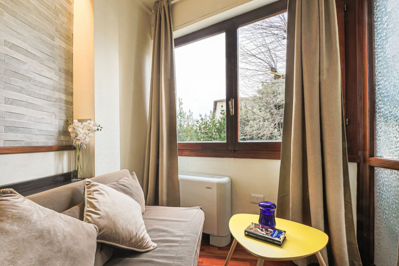 Una habitación con sofá, una mesita, una ventana con cortinas y un radiador.