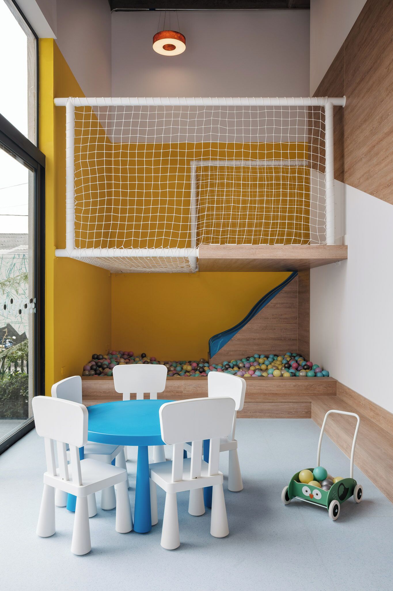A play area with a netted climbing structure, a slide, and a ball pit.