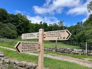 A wooden directional signpost with multiple arrows pointing to different trails. - A cosy stone cottage with stunning views, village charm, and adventure at your doorstep (Richmond)