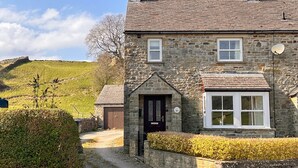 A stone house with a traditional design, featuring a central door, two windows, and a satellite dish.