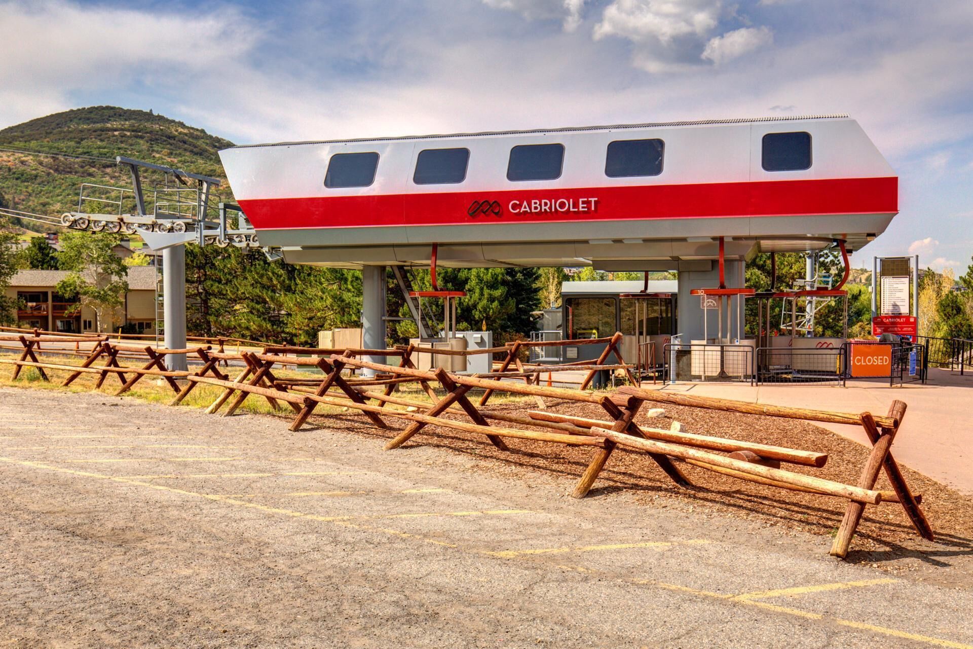 Une station-service avec un logo Cabriollet rouge et blanc, des pompes à essence et une clôture en bois au premier plan.