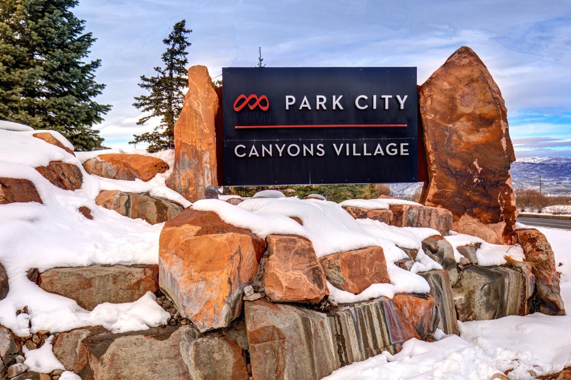 Opastekyltti, jossa lukee Park City Canyons Village, ja taustalla näkyy vuoristomaisema.