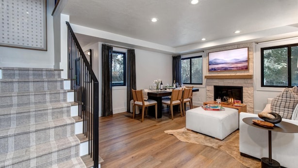 A modern living room with a fireplace, dining area, and a staircase.