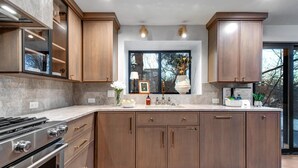 A modern kitchen with wooden cabinets, a stainless steel stove, and a large island with a sink.