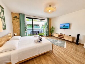 Une chambre d’hôtel avec un lit, une télévision, une commode en bois et un balcon avec vue.