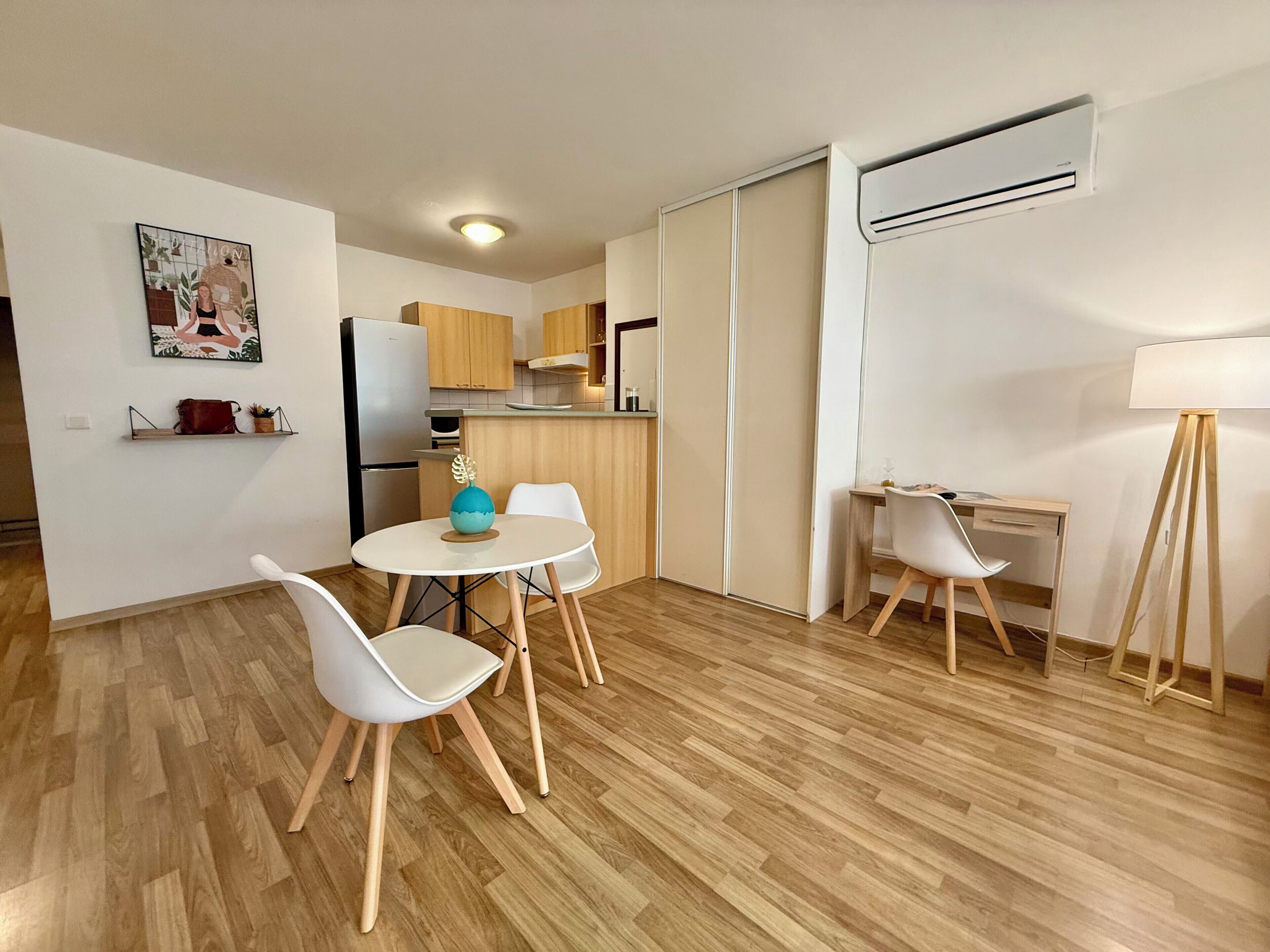 A compact living space with a dining area, kitchenette, and a workspace.