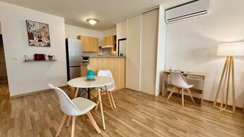 A compact living space with a dining area, kitchenette, and a workspace.
