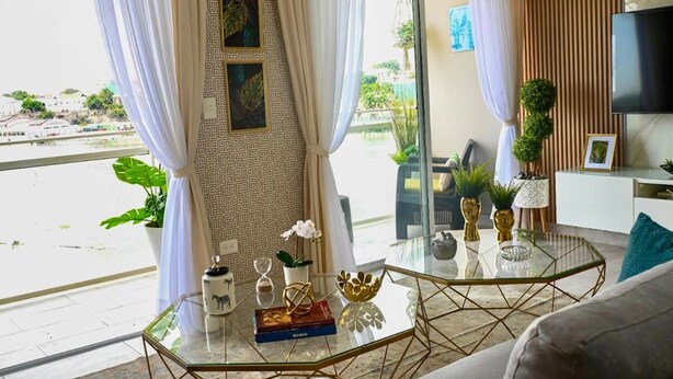 Un salon moderne avec une table basse en verre, un canapé et un téléviseur fixé au mur.