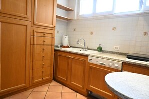 Ett kök med träskåp, en inbyggd diskmaskin, en diskho och ett fönster ovanför bänkskivan.