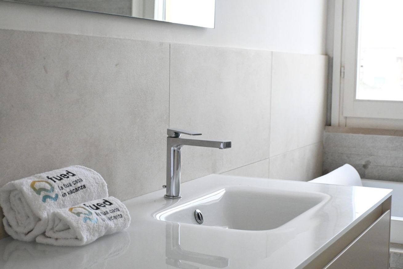 Une salle de bain avec un lavabo blanc, un robinet moderne et deux serviettes ornées de motifs.