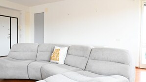 A modern living room with a grey sectional sofa, a white accent pillow, and a wooden floor. - N297 - Numana, three-room apartment in the heart of the town (Numana)