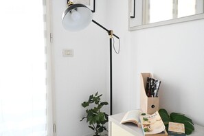 Une pièce comprenant un bureau, une plante, une lampe et une bibliothèque remplie de livres et de magazines.