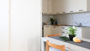 A kitchen with white cabinets, a grey countertop, and a dining table with chairs. - CV001 – Cervia, comfortable studio apartment on the ground floor (Cervia)