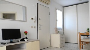 A room with a television, a desk, a chair, a wardrobe, and a mirror. - CV001 – Cervia, comfortable studio apartment on the ground floor (Cervia)