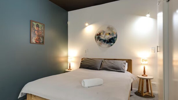 Een slaapkamer met een bed, twee bedlampen, een wanddecoratie en een ronde decoratie aan de muur.