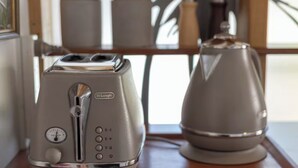 Een DeLonghi toaster en waterkoker op een houten tafel.