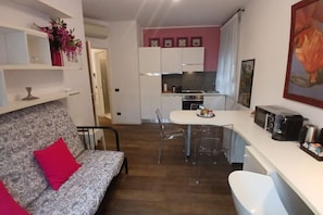 A compact living space with a sofa, a dining table, a kitchen area, and a small bar counter. - CN008 - Cesenatico, new two-room apartment 30m from the canal (Cesenatico)