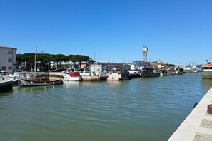 Un port de plaisance avec des bateaux amarrés, un ciel dégagé et des bâtiments en arrière-plan.
