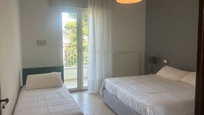 A bedroom with two beds, a window with curtains, a ceiling light, and a view of the outside. - CV004 - Cervia, new three-room apartment with air conditioning (Cervia)