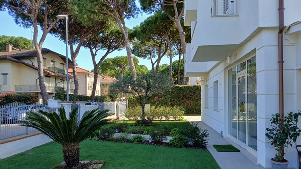 A modern building with a well-maintained garden, including a palm tree and various shrubs. - CV004 - Cervia, new three-room apartment with air conditioning (Cervia)