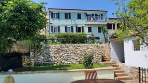 Ein Gebäude mit einer Steinwand, einem Balkon und einem Tisch mit Stühlen im Vordergrund.