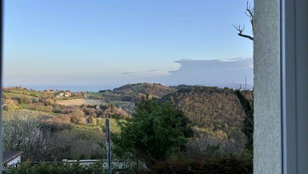 Blick auf eine Küstenlandschaft mit Hügeln und einem Gewässer.