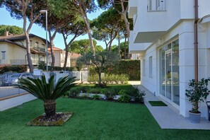 A modern building with a well-maintained garden, including a palm tree and various shrubs.