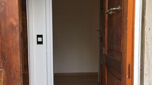 Een gang met een houten deur aan de rechterkant en een witte deur aan de linkerkant.