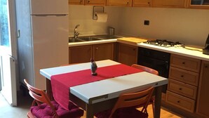 Een compacte keuken met houten kastjes, een gasfornuis, een spoelbak en een koelkast.