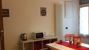 Een eetgedeelte met een tafel, stoelen, een magnetron, een waterkoker en een klein beeldje.