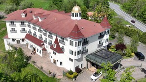 A large, multi-story building with a red roof and a central tower. - Aspiratinns Hotel & Wellness Center (Slate Hill)