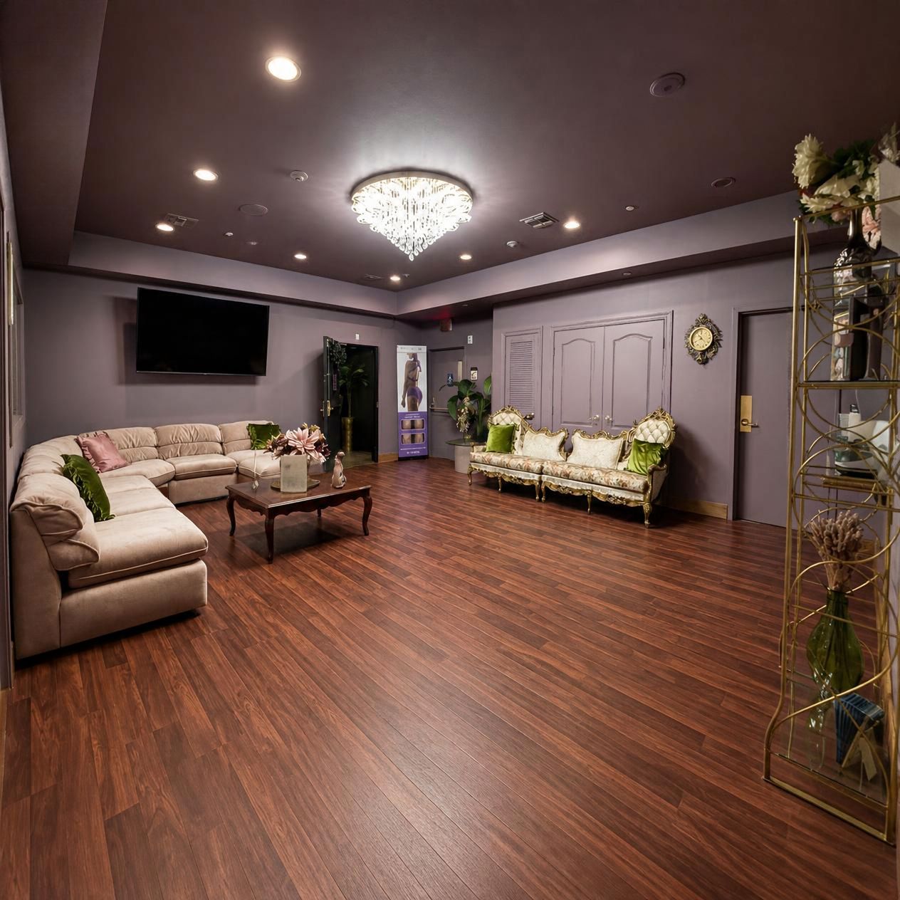 A spacious living room with a large sectional sofa, a smaller sofa, a coffee table, and a chandelier.