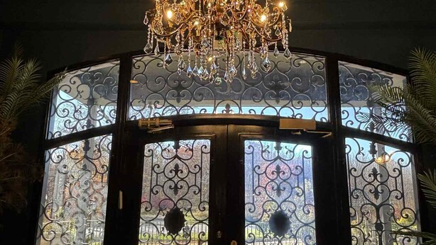 A room with a large, ornate chandelier and a glass partition with intricate metalwork. - Aspiratinns Hotel & Wellness Center (Slate Hill)