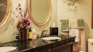 A bathroom with two large mirrors, a dark wooden vanity, a white sink, a towel rack with multiple towels, and a toilet. - Aspiratinns Hotel & Wellness Center (Slate Hill)