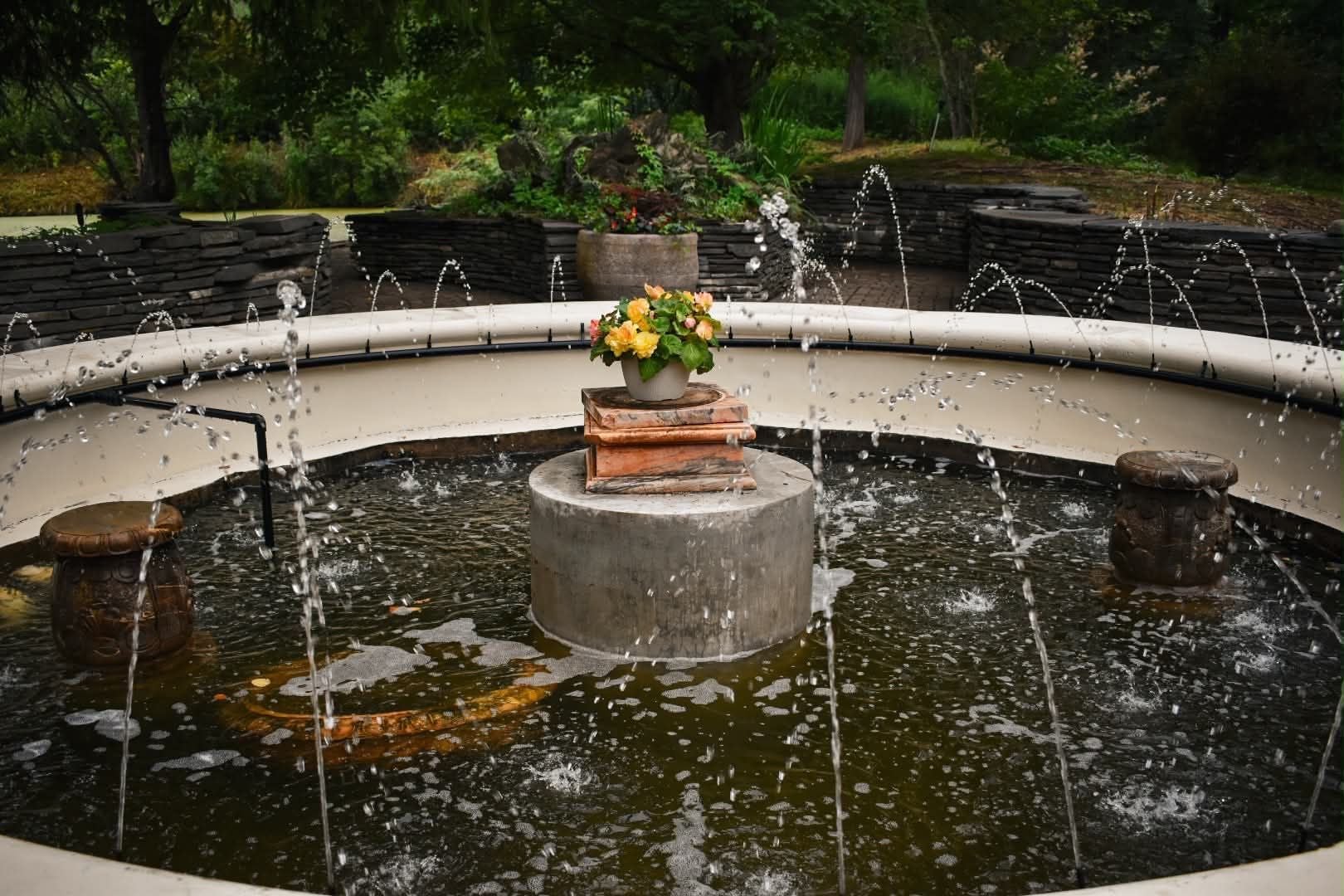 A circular water feature with a central platform, surrounded by a stone wall.
