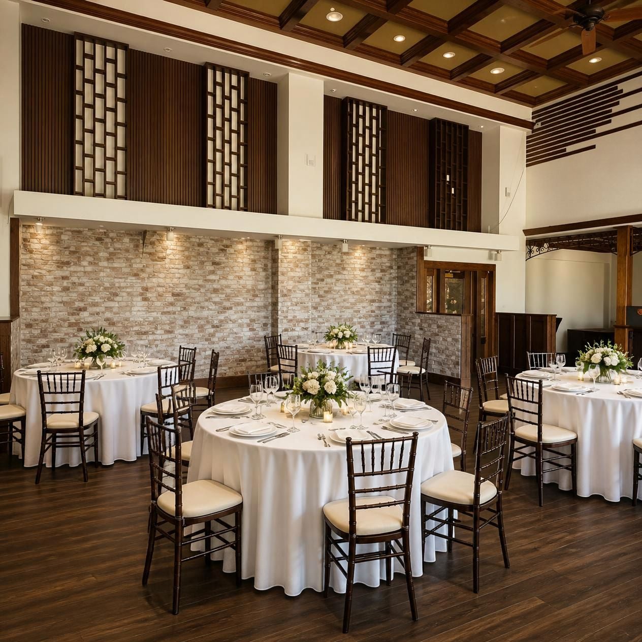 A banquet hall with multiple round tables, each set with white tablecloths, chairs, and floral centerpieces.