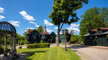 A historic building with a tower, surrounded by a well-maintained lawn and cobblestone paths.