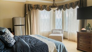 A hotel room with a bed, a dresser, a television, and a window with curtains. - Aspiratinns Hotel & Wellness Center (Slate Hill)