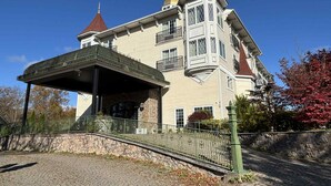 Un edificio grande y ornamentado con una torre destacada y un acceso cubierto.