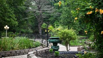 A garden with a curved metal fence, a stone pathway, and a green decorative urn.