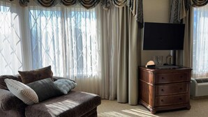 A cozy living room with a brown sofa, a wooden dresser, and a flat-screen TV. - Aspiratinns Hotel & Wellness Center (Slate Hill)