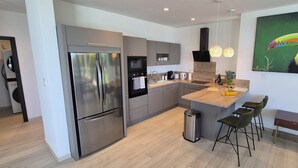 Una cocina moderna con electrodomésticos de acero inoxidable, una isla central y un cuadro de un tucán.