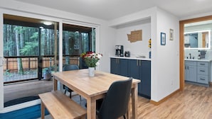 Una cocina moderna con armarios azul oscuro, una mesa de comedor de madera y una cafetera.