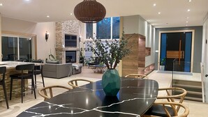 A modern dining area with a black marble table, wooden chairs, and a decorative vase. - Spacious Retreat in the Pines • Walk to Georgian Bay Beaches (Tiny)