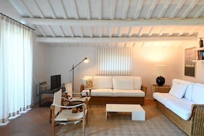 A living room with a sofa, chairs, a coffee table, a lamp, and a television.
