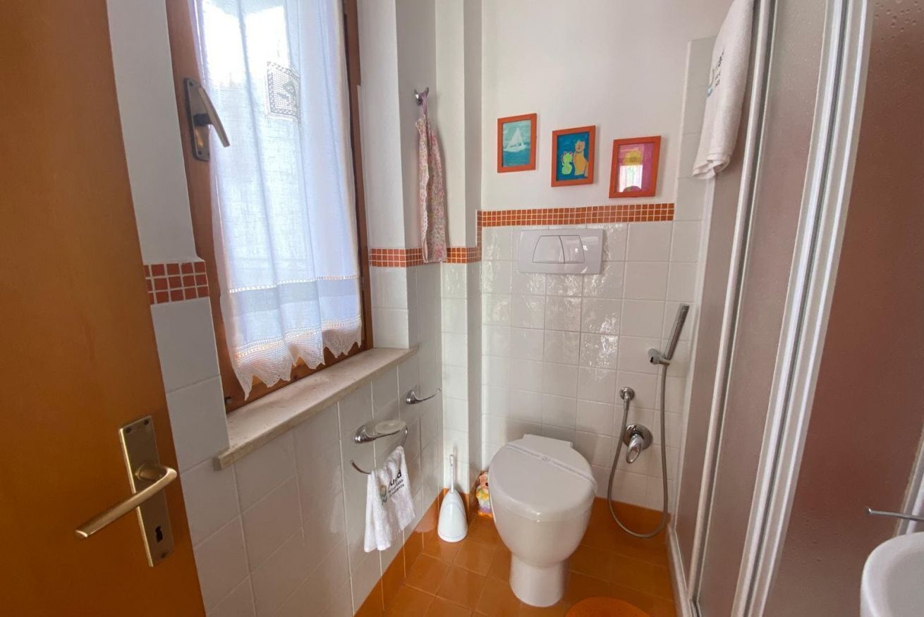 Ein Badezimmer mit Toilette, Dusche und einem Fenster mit Vorhängen.