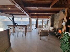 Un salón espacioso con vistas al mar, una chimenea y un comedor con una computadora portátil.