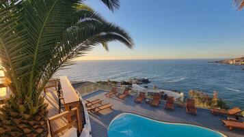 A poolside area with lounge chairs and a view of the ocean.