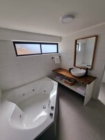 Un baño moderno con una bañera independiente, un tocador con lavamanos y un espejo grande.