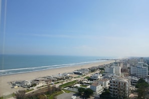 A coastal cityscape with a beach, buildings, and a clear sky.